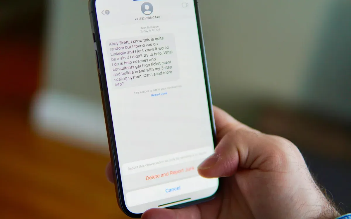Mano sostiene un teléfono que muestra una conversación de mensajes