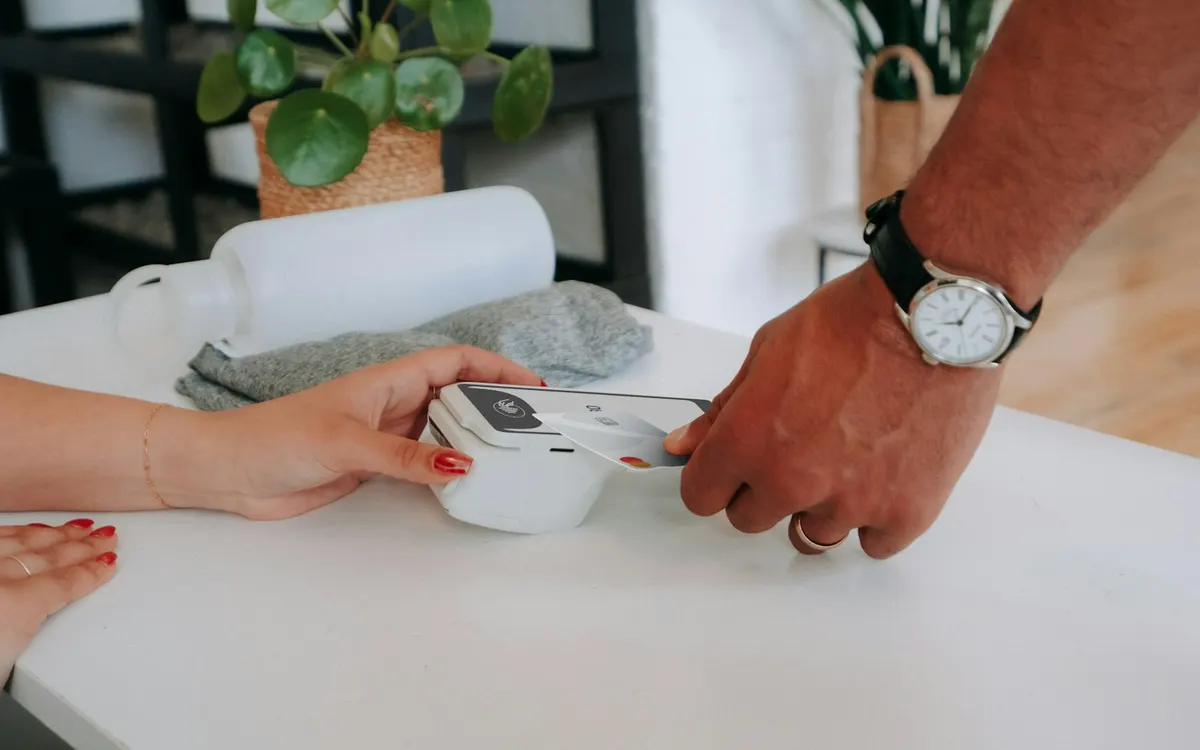 Cliente acerca una tarjeta bancaria a un terminal de pago en una tienda