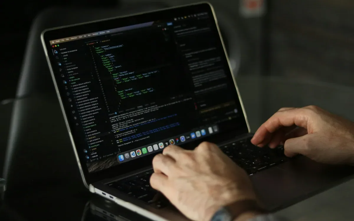 Manos escribiendo código en un notebook durante una tarea de mantenimiento web