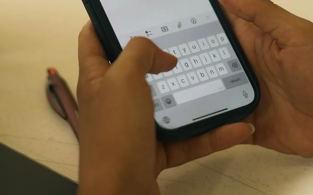 Manos escriben un mensaje en el teclado de un telefono movil